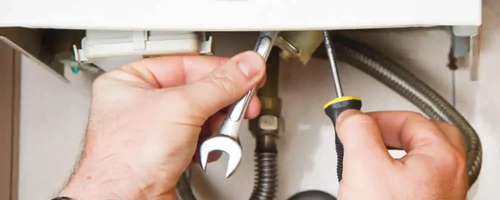 Boiler repair technician tightening pipe fittings and connections in Houston, TX