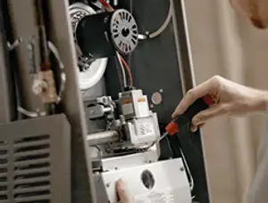 Furnace repair technician inspecting internal components and wiring in Houston, TX