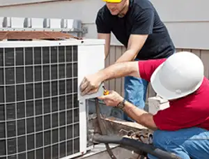 HVAC technicians repairing an outdoor AC unit on a rooftop in Houston, TX