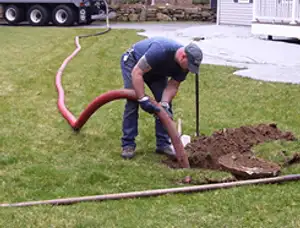 Septic pumping technician servicing a residential septic tank with a vacuum hose in Houston, TX