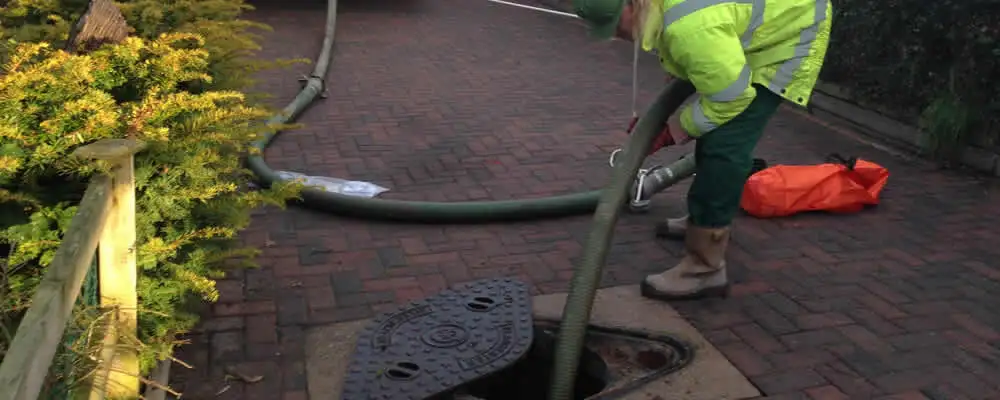 Septic tank cleaning technician servicing a septic tank with a vacuum hose in Houston, TX